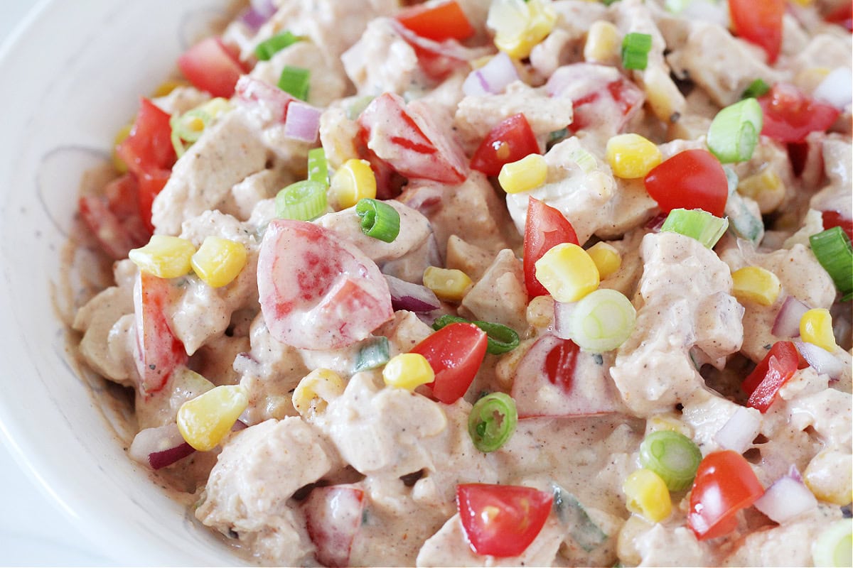 Up close side photo of creamy bbq salad with fresh tomatoes and corn.