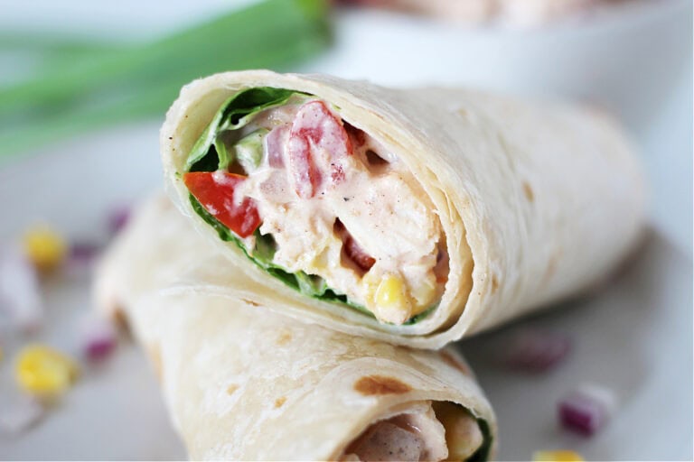 Up close photo of creamy bbq chicken salad in a tortilla with lettuce.