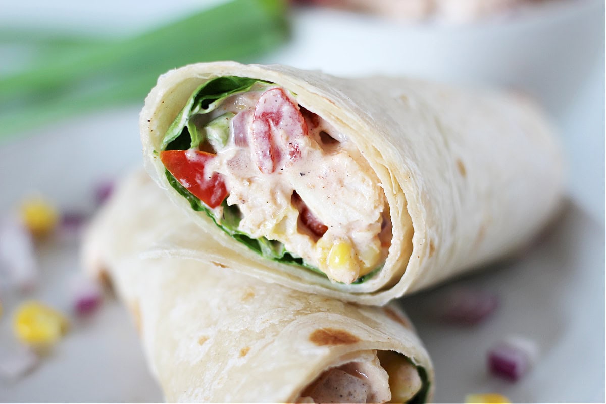 Up close photo of creamy bbq chicken salad in a tortilla with lettuce.