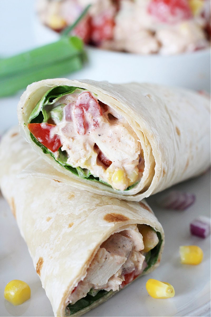 Two halves of a creamy bbq chicken salad wrap stacked on top of each other.