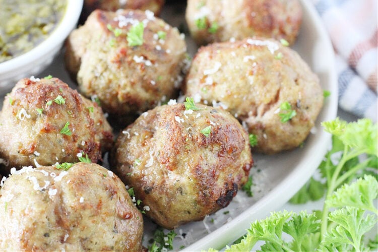 Up close air fryer turkey pesto meatballs topped with chopped parsley and shredded parmesan.