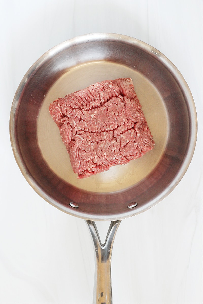 Overhead photo of raw ground beef in a stainless steel sauté pan.