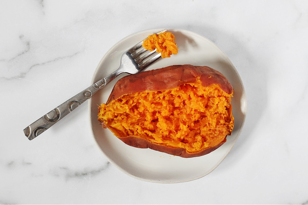 Overhead photo of a sweet potato cut in half and fluffed with a fork.