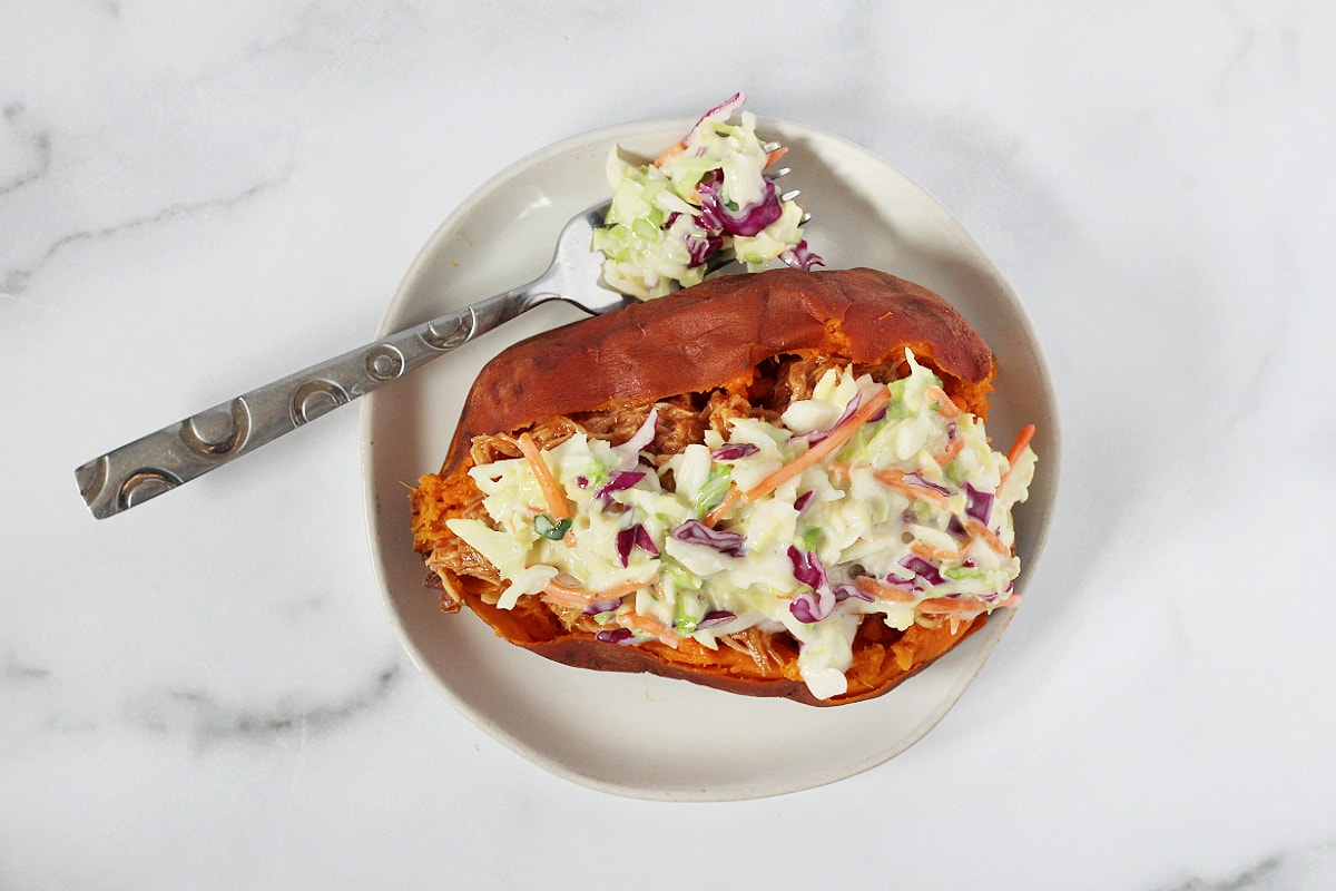 Overhead photo of a cooked sweet potato stuffed with BBQ chicken and coleslaw.