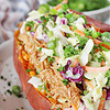 A sweet potato stuffed with bbq chicken and coleslaw.