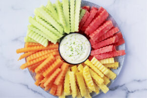 Overhead photo of four different kinds of fruit fries on a platter with yogurt dip.