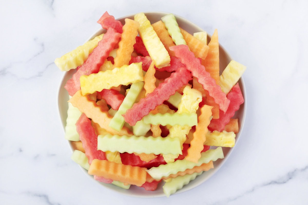 Overhead photo of a white plate stacked high with four different kinds of fruit fries.