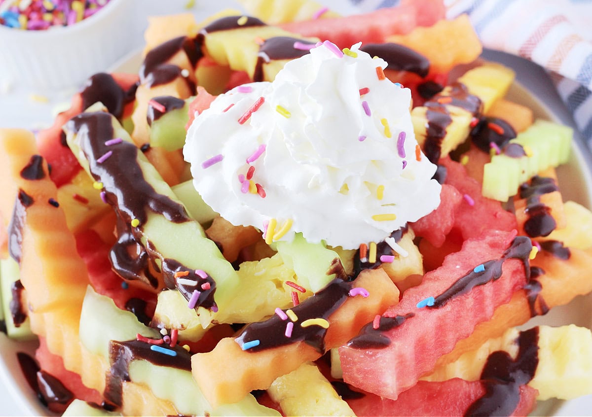 Fruit fries topped with whipped cream, chocolate sauce and rainbow sprinkles.