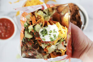 A hand holding a taco in a bag of high protein Quest tortilla chips.