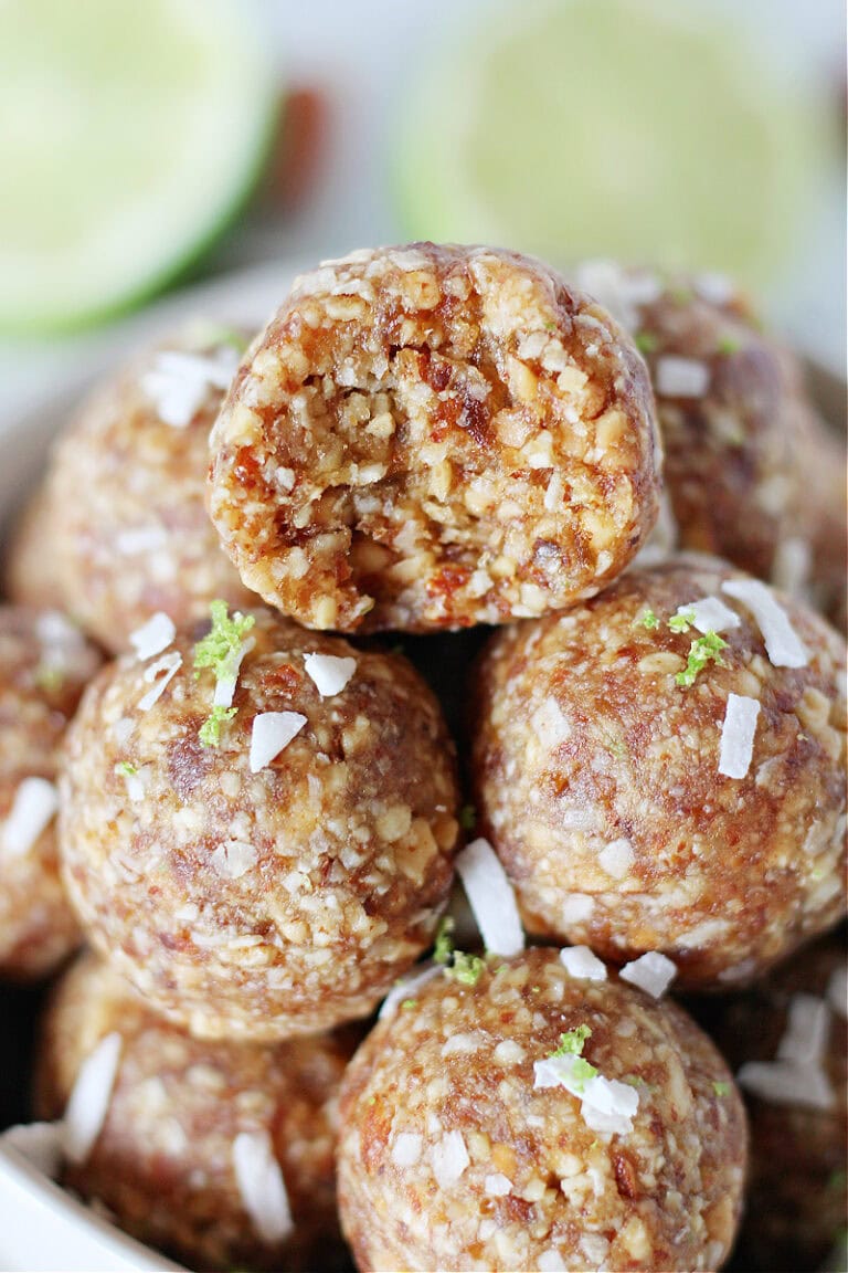 Coconut energy balls piled high in a bowl topped with lime zest.