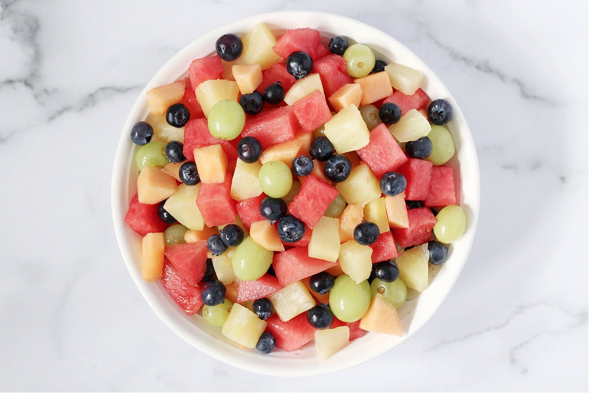 Overhead photo of a white bowl filled with 5 ingredient fresh fruit salad.