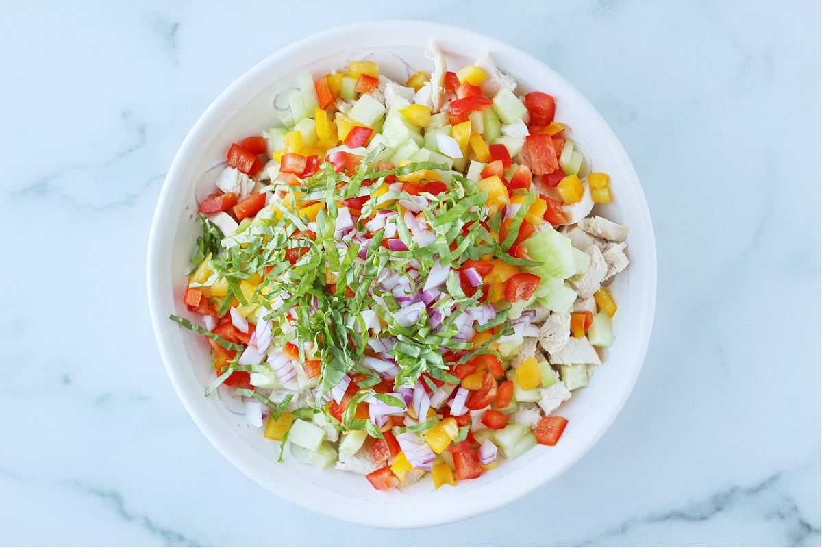 Overhead photo of all the ingredients for a rice salad layered in white bowl.