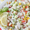Up close photo of a chicken and rice salad with fresh basil and lemon slices.