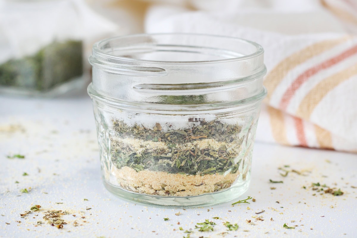 Spices for Italian seasoning layered in a small mason jar.