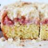 Up close side shot of the 3 layers of strawberry coffee cake with a glaze.