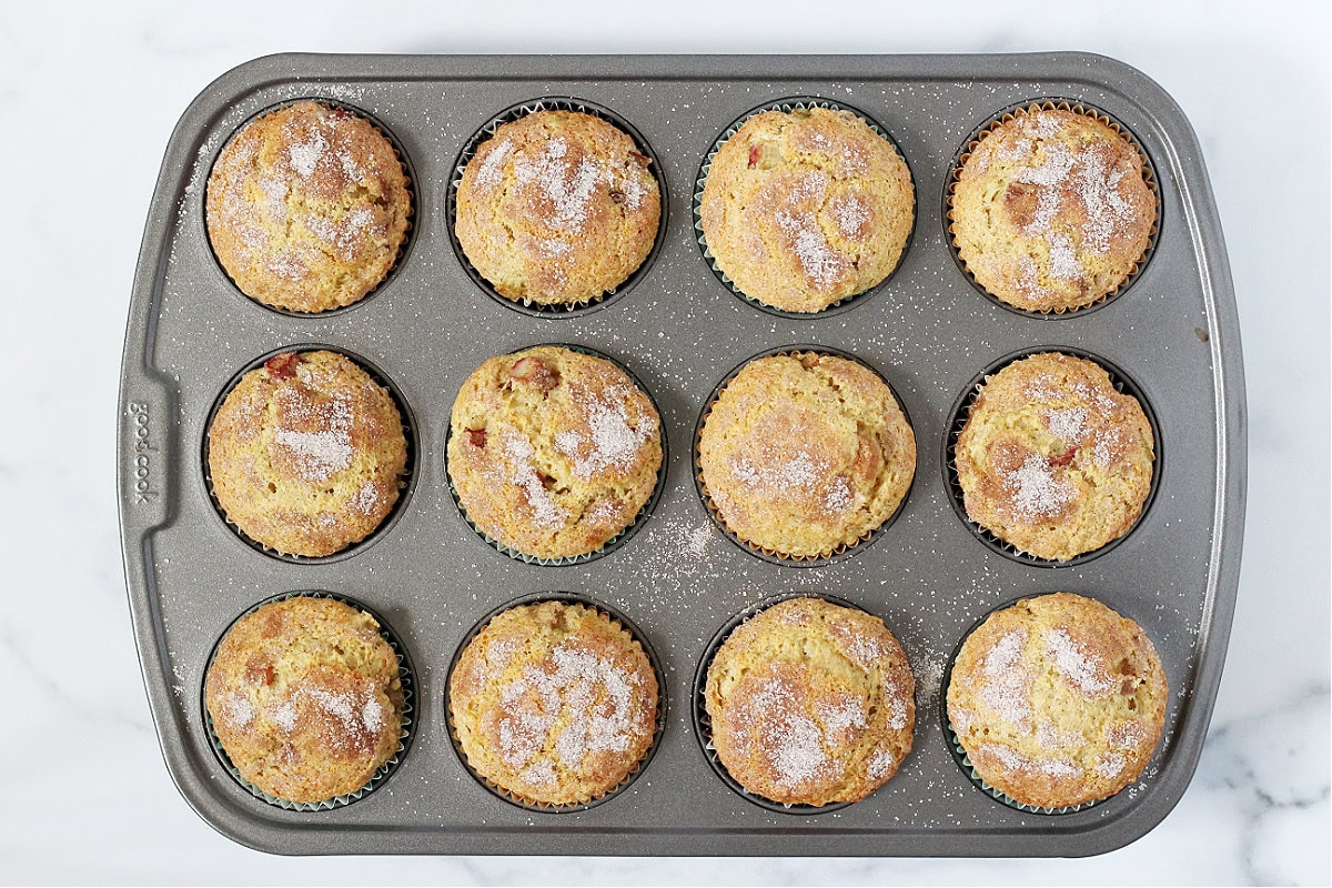 Overhead photo of twelve baked rhubarb muffins in a muffin pan.