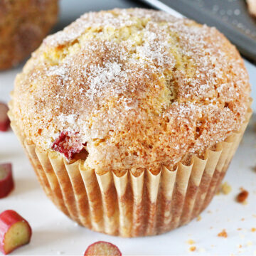 Up close photo of a rhubarb muffin topped with cinnamon sugar ready to be eaten.