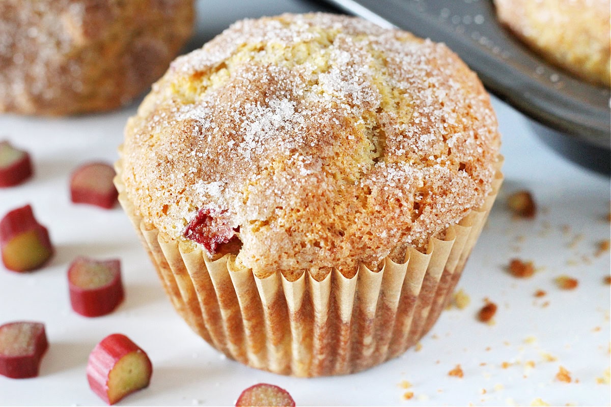 Up close photo of a rhubarb muffin topped with cinnamon sugar ready to be eaten.