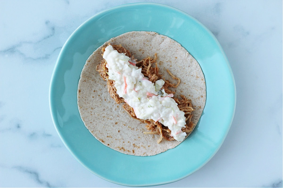 Overhead photo of a tortilla topped with BBQ chicken and coleslaw.