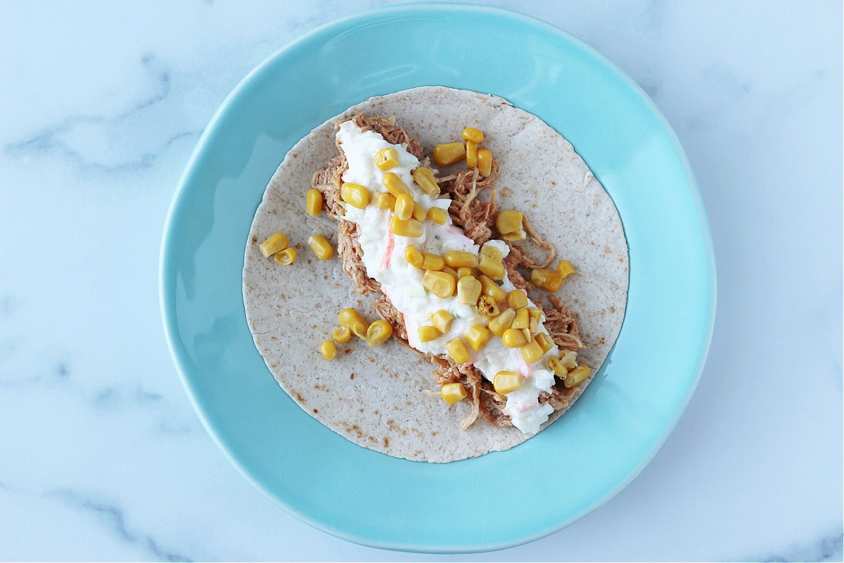 Overhead photo of a BBQ chicken taco topped with fire roasted corn.