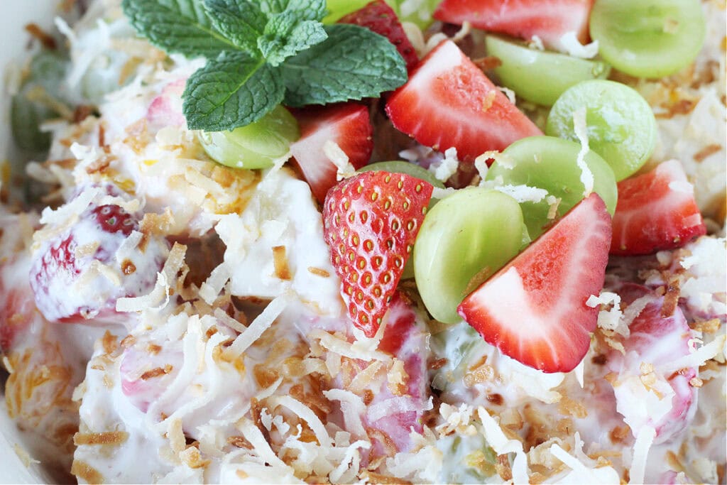 Up close photo of a summer fruit salad coated in coconut vanilla Greek yogurt.