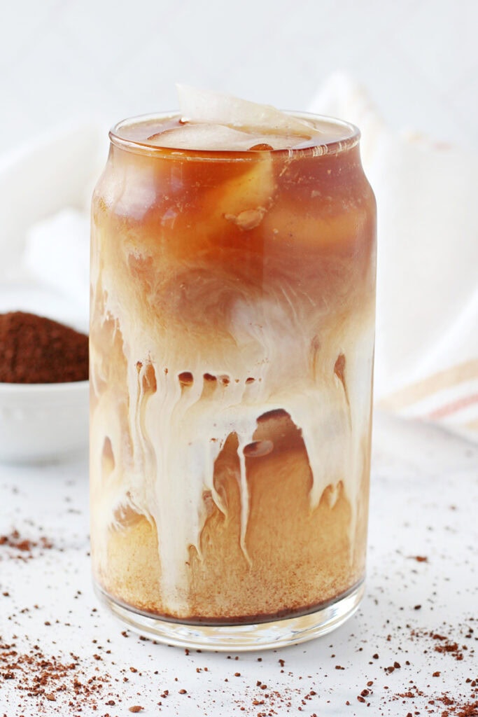 Half and half pouring through a glass of ice and cold brew coffee.