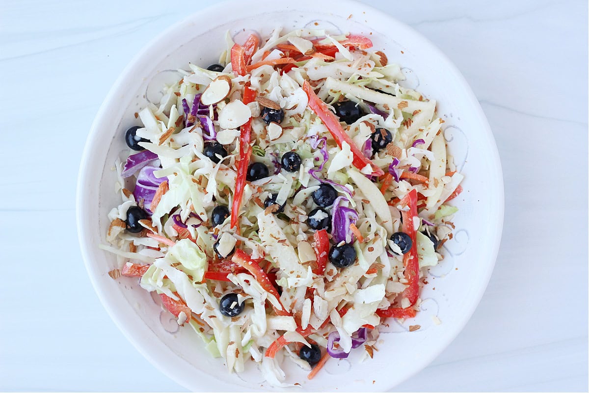 Overhead photo of a red, white and blue cabbage salad topped with sliced almonds.