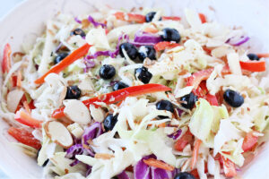 Sliced red bell peppers, blueberries and cabbage slaw in a white bowl.