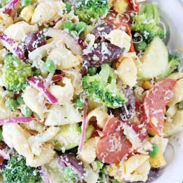 Overhead photo of a healthy loaded veggie pasta salad topped with shredded Parmesan cheese.