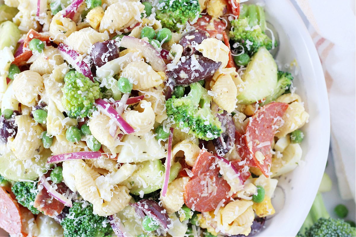 Overhead photo of a healthy loaded veggie pasta salad topped with shredded Parmesan cheese.