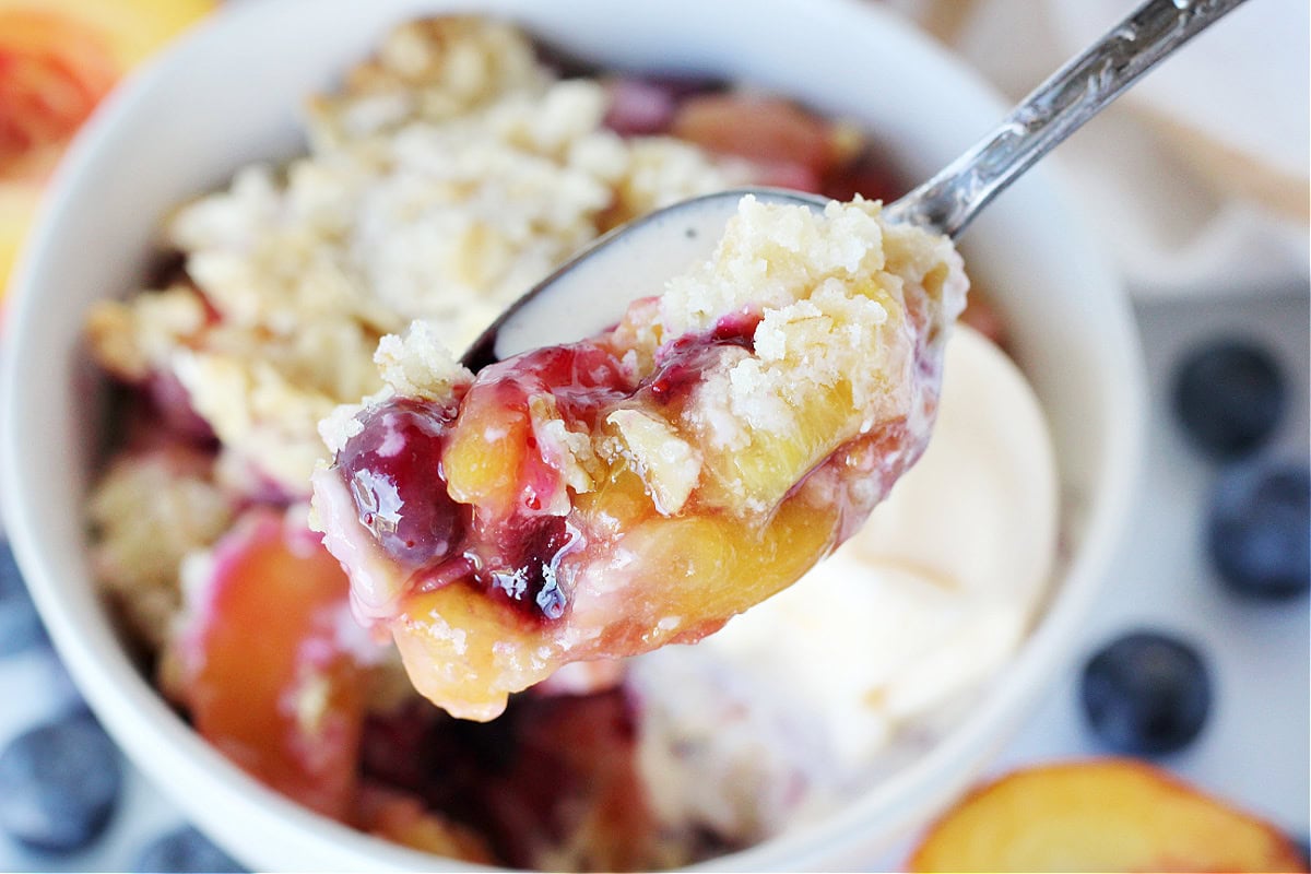 Up close photo of blueberry peach crumble on a spoon.