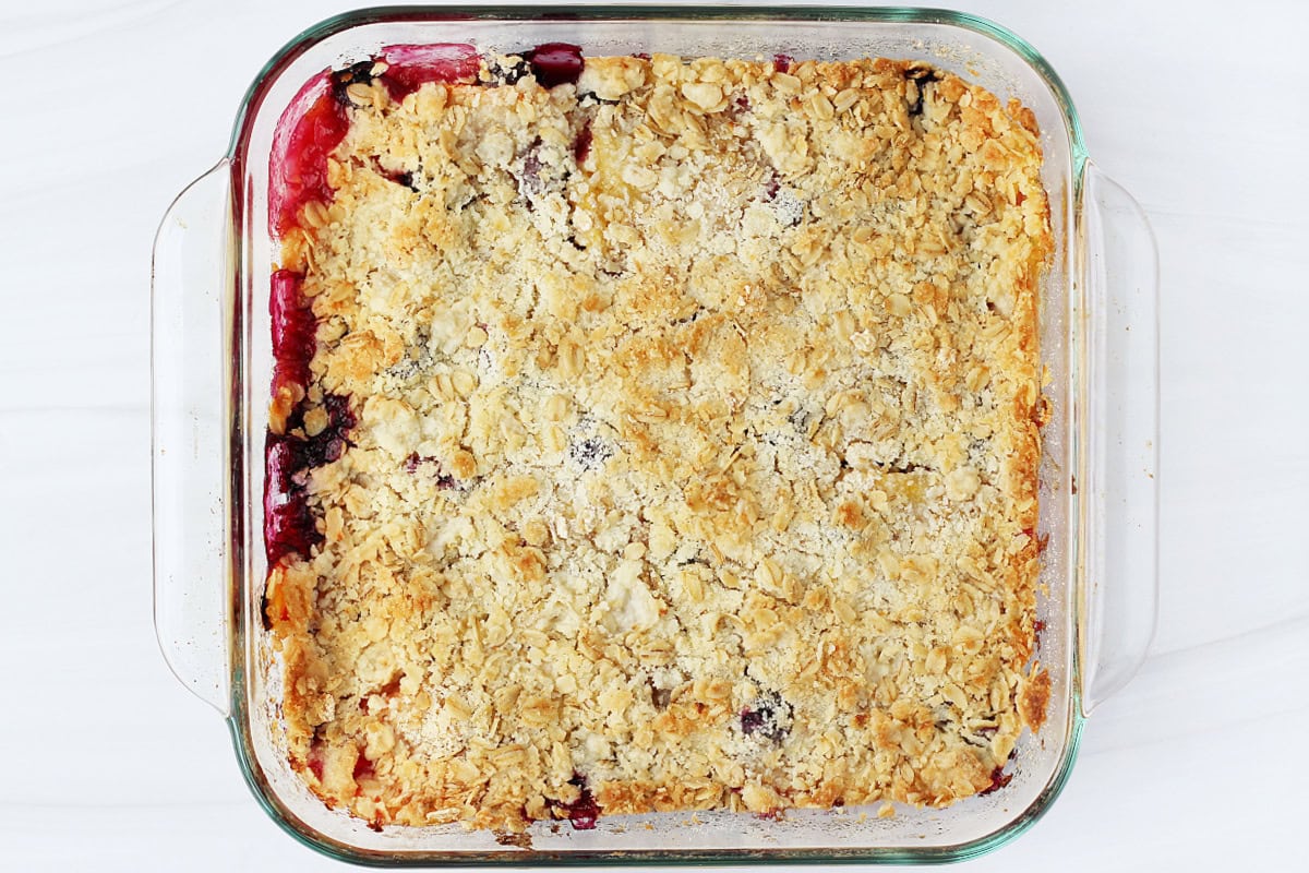 Overhead photo of a baked low sugar peach crumble in an 8x8 glass pan.