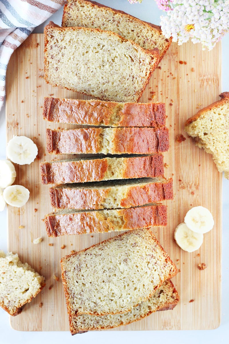 Overhead photo of a loaf of banana bread cut into slices on a cutting board.