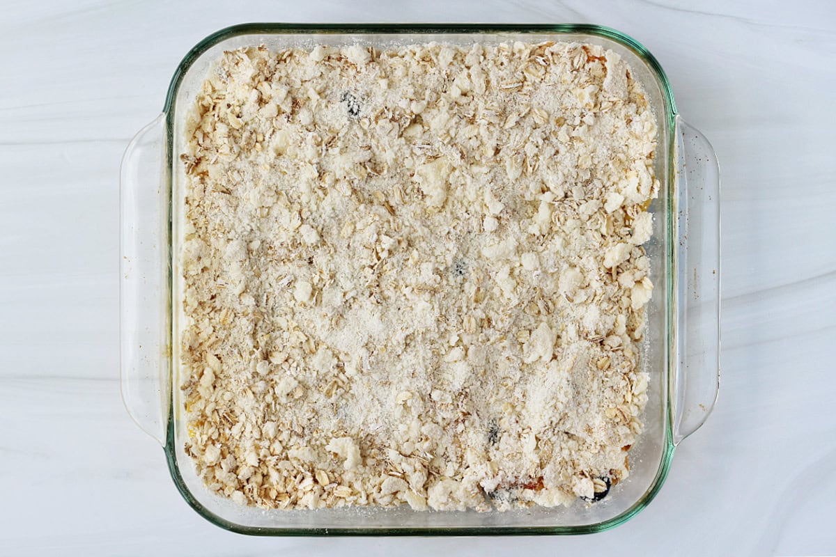 Overhead photo of crumble topping on top of peaches and blueberries.