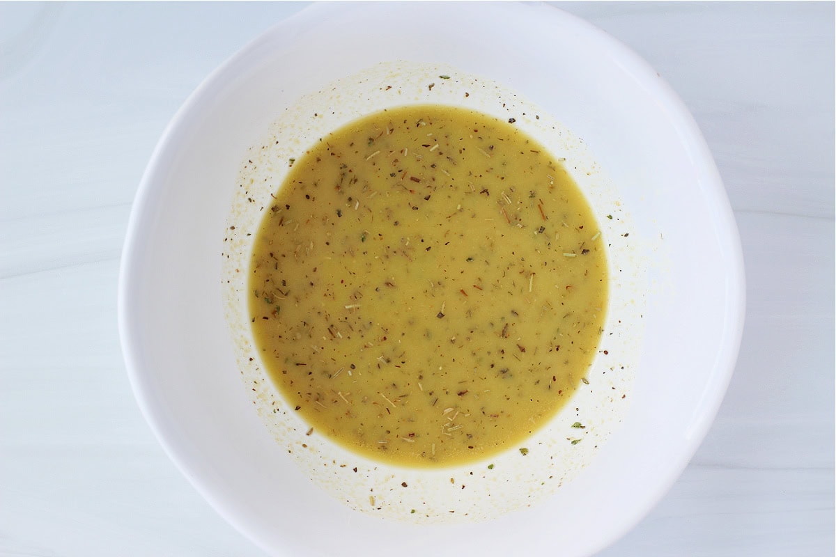 Overhead photo of a lemon and olive oil dressing with Italian seasoning.