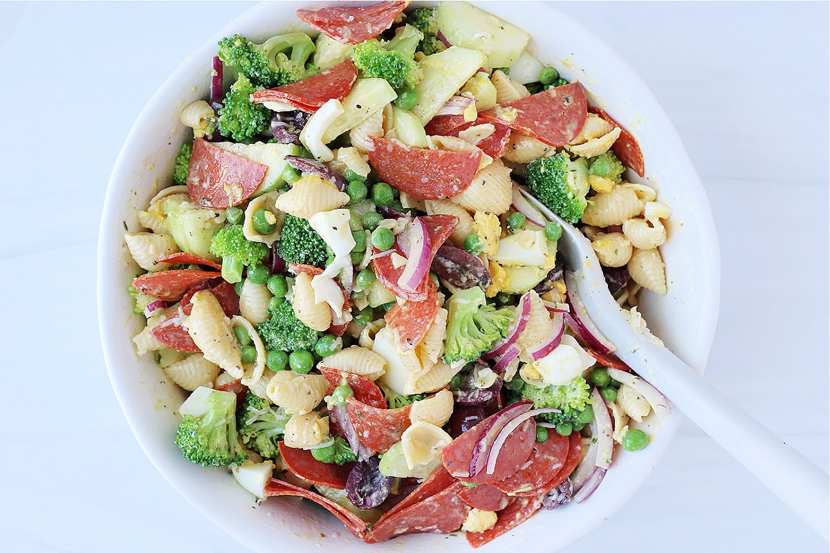 A spoon mixing up the ingredients of a high protein pasta salad.