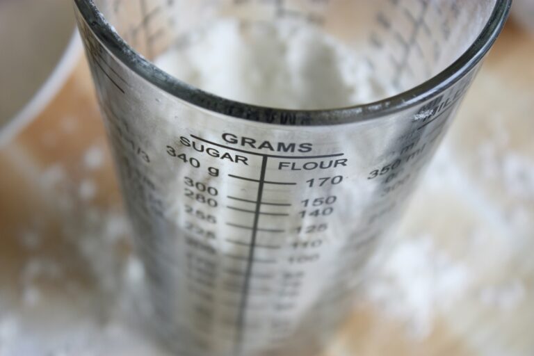 Up close photo of a measuring glass with grams of sugar and flour.