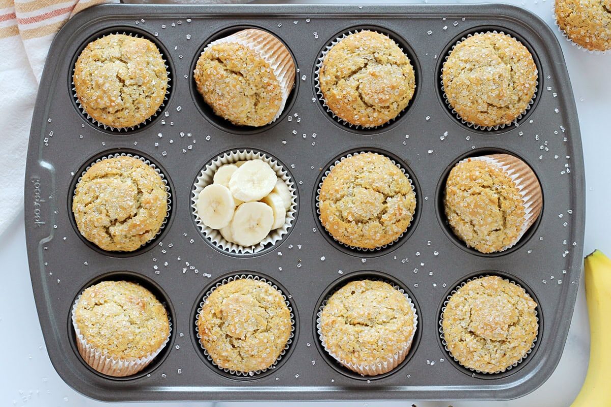 Banana muffins in a pan with fresh banana coins.