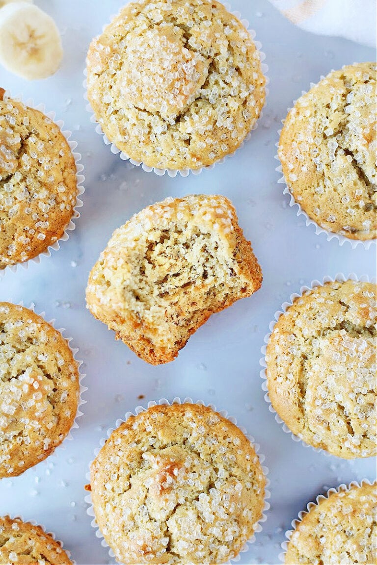 Overhead photo of banana muffins with the middle one having a bite taken out.