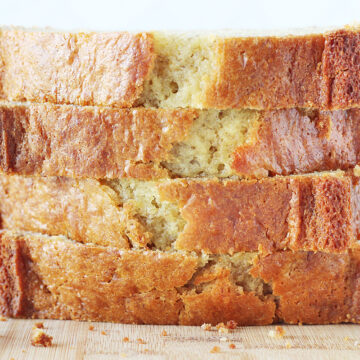 Up close photo of a stack of four thick slices of banana bread.