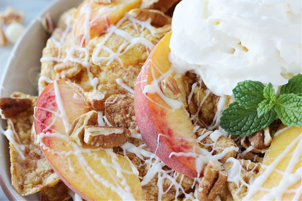 Up close photo of sliced peaches and pecans with white chocolate on cinnamon chips.