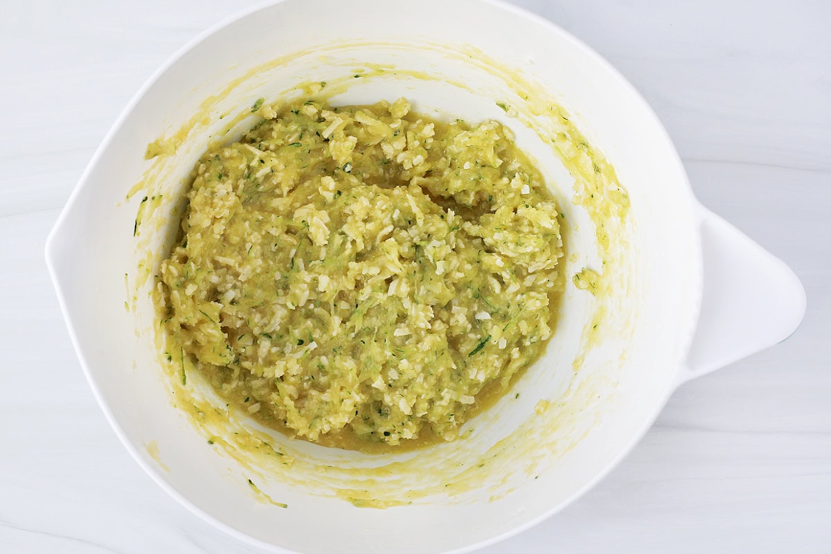 Overhead photo of shredded zucchini and coconut shreds mixed into a cookie batter.