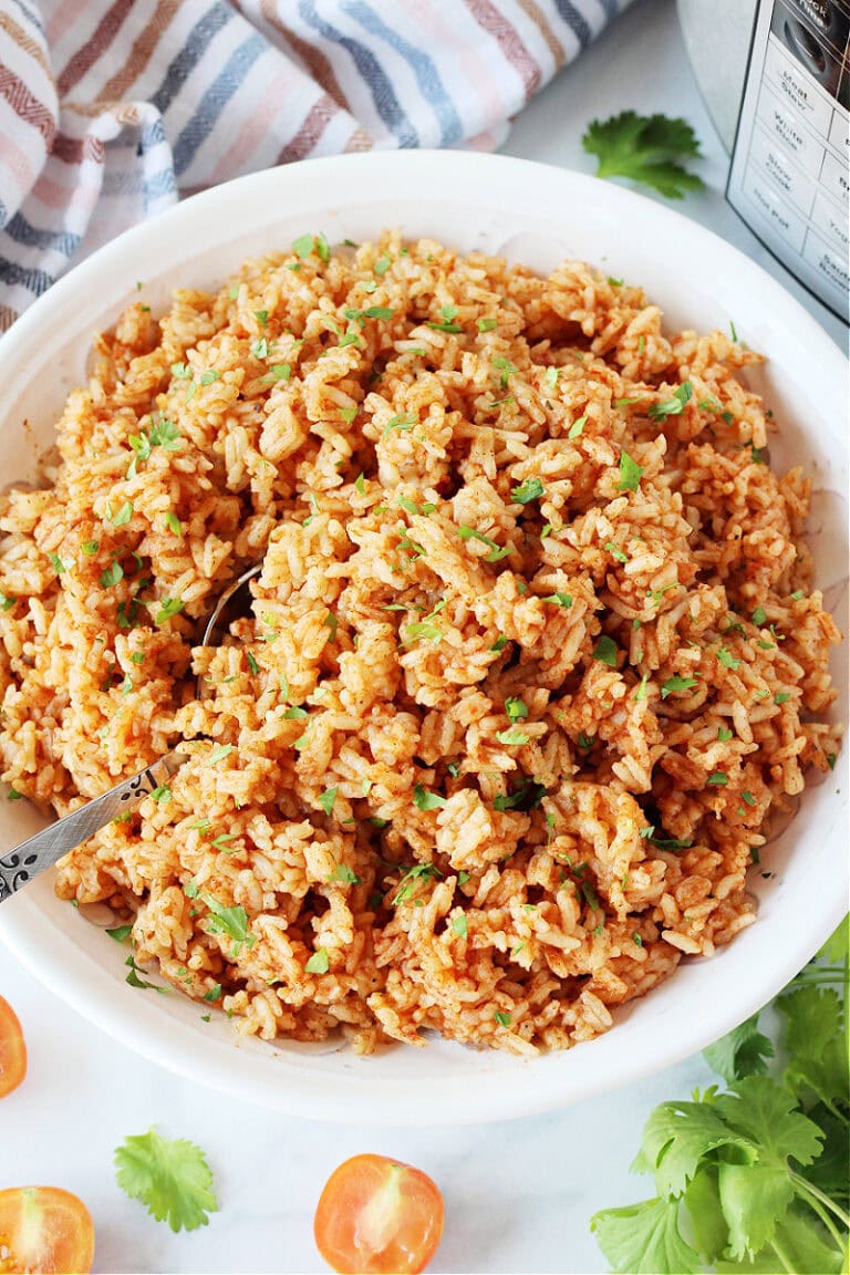 Mexican Rice in a white serving bowl garnished with chopped cilantro.