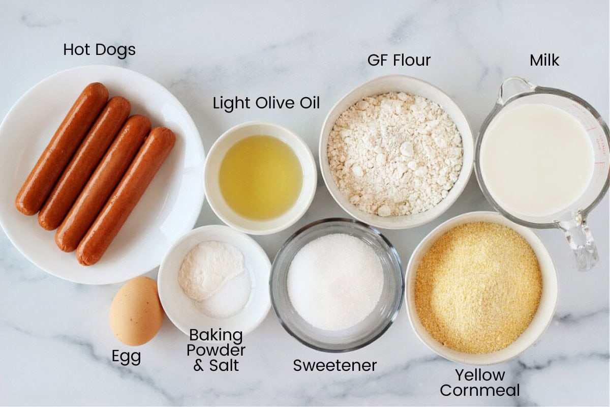 Ingredients in bowls for mini corn dog muffins on a white countertop.