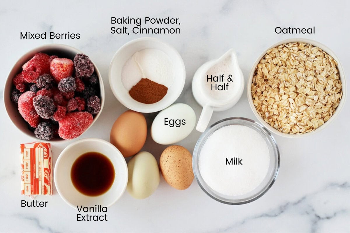 Ingredients for mixed berry oatmeal bake on a white marble countertop.