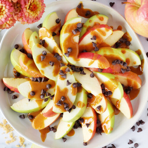 Overhead photo of sliced apples drizzled with a peanut butter caramel sauce and chocolate chips.