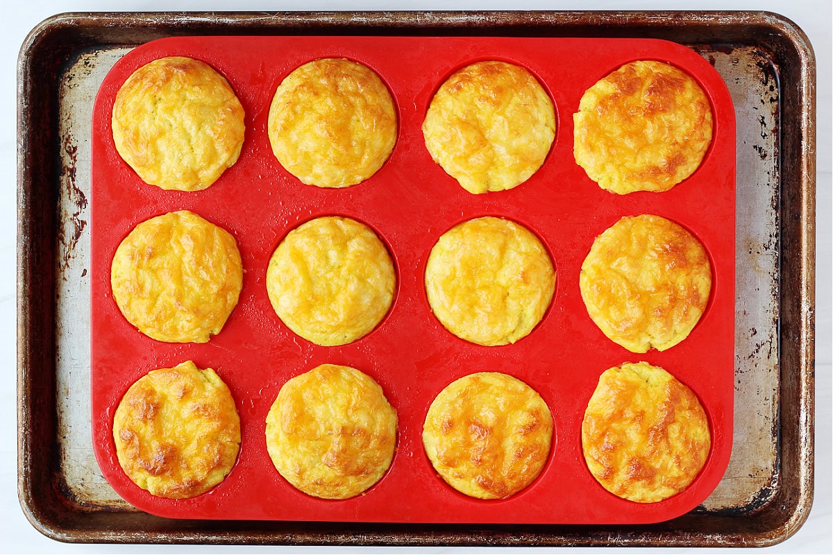 Twelve baked egg muffins in a silicone pan on a metal sheet pan.