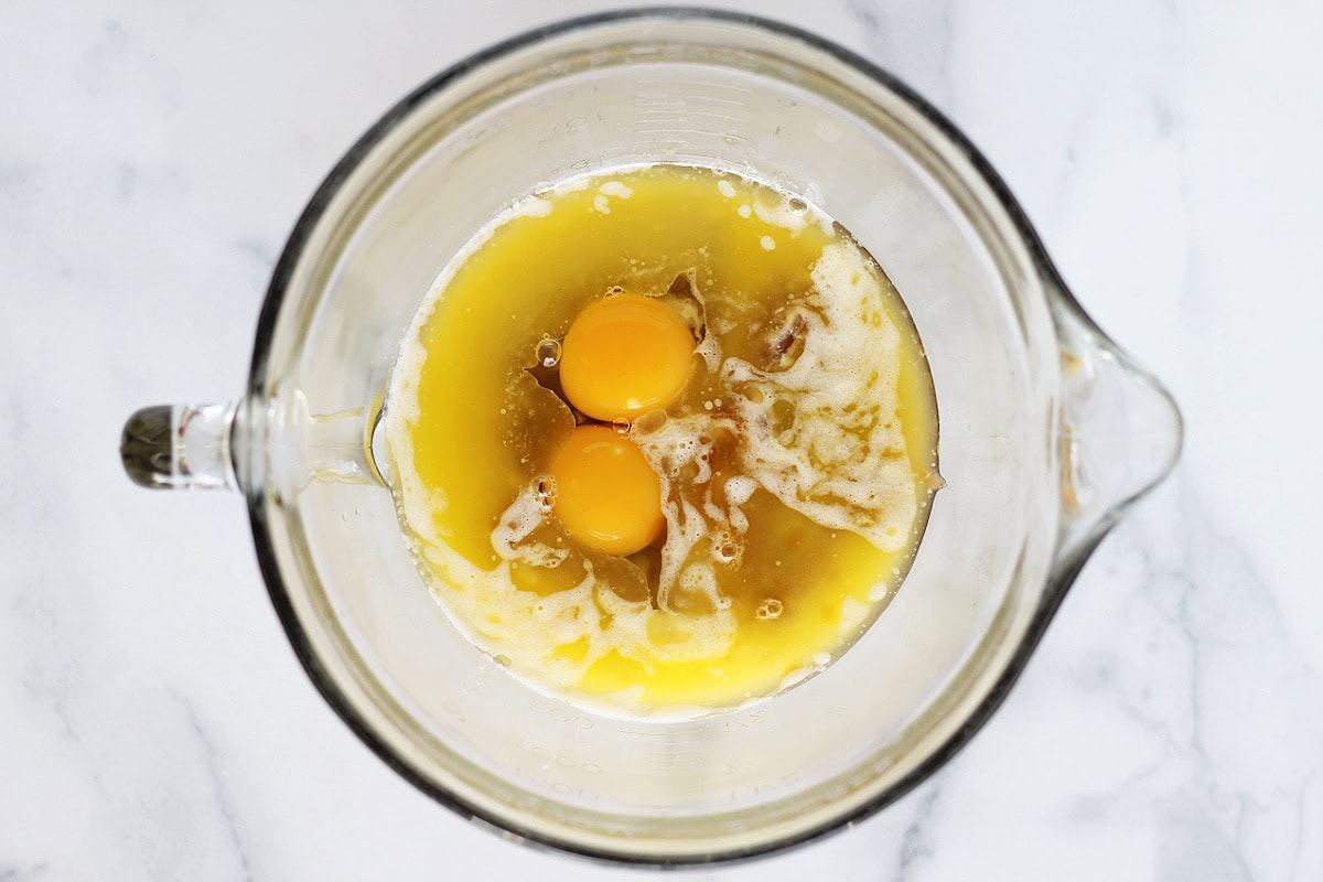 Two eggs in melted butter and apple butter in a glass bowl.