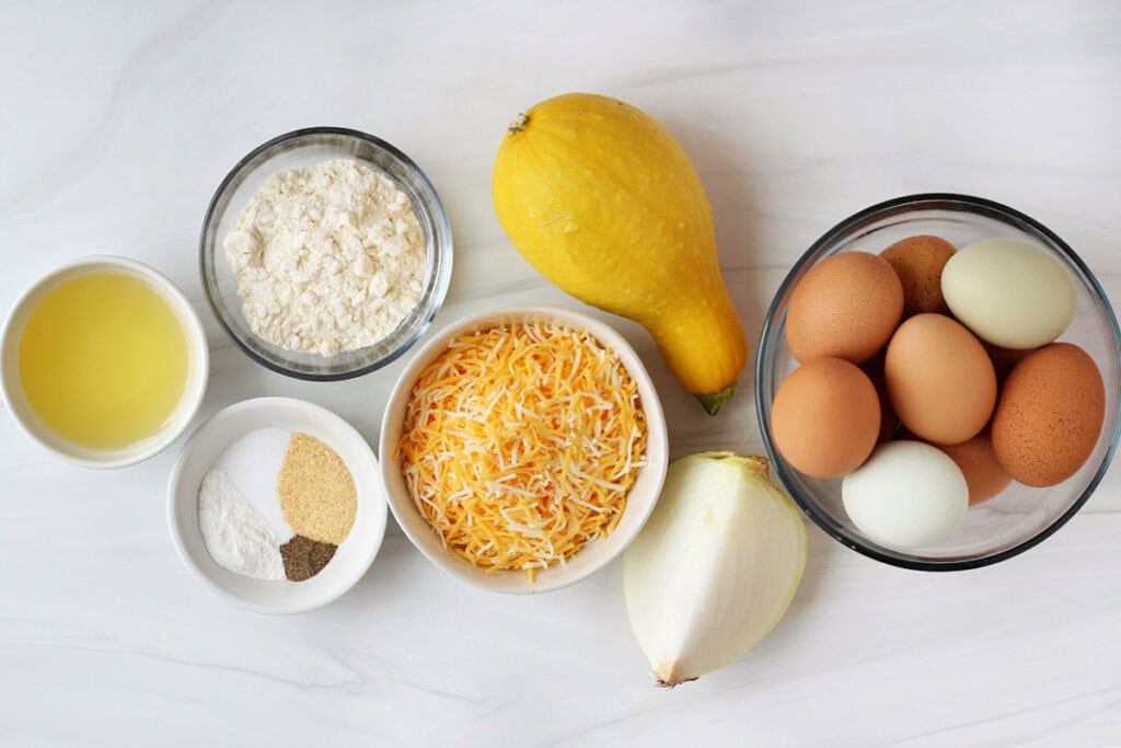 Ingredients for a breakfast egg muffin recipe on a white marble countertop.