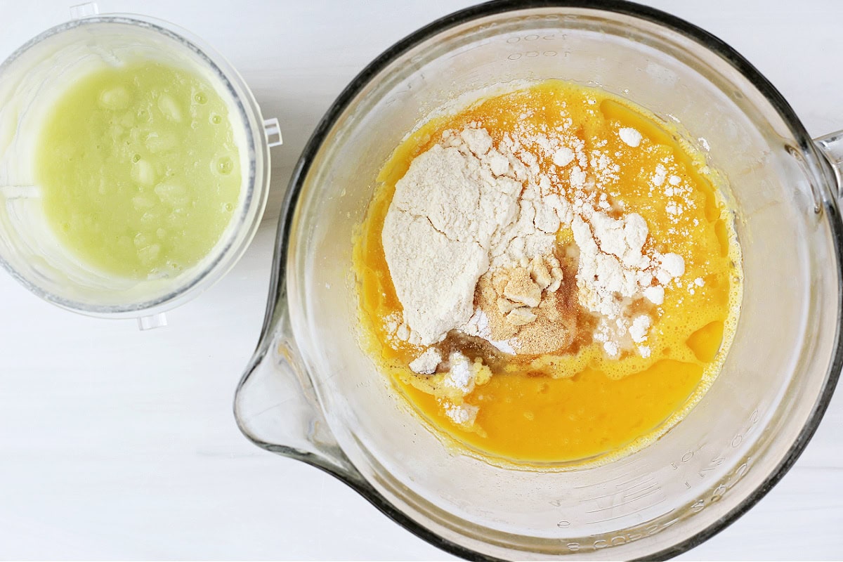 Overhead photo of an egg mixture in a bowl with pureed veggies in a cup.